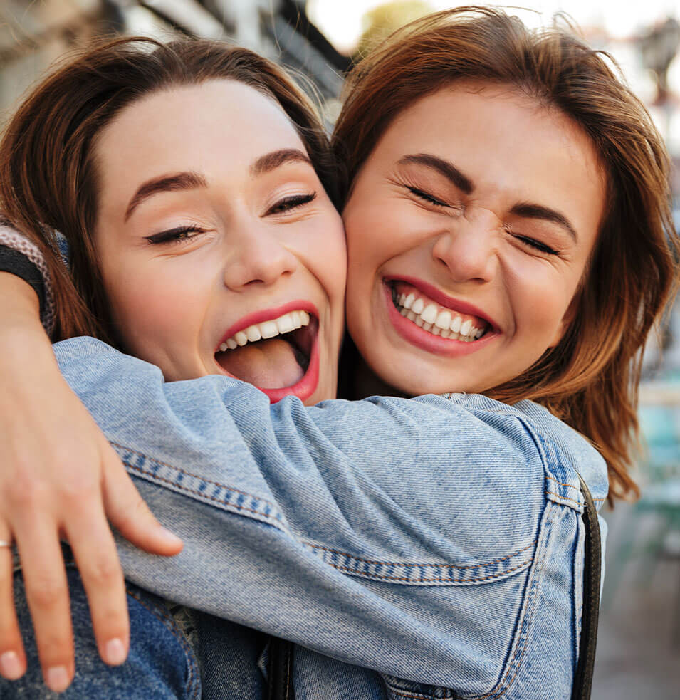 Two girls smiling at the camera after Invisalign treatment | Loughborough Orthodontics
